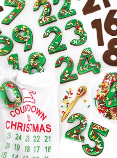 the numbers are green and brown with sprinkles on them next to a bag of doughnuts