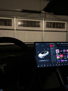 a laptop computer sitting on top of a desk in front of a car door and garage