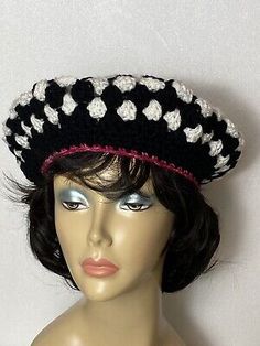 a mannequin head wearing a black and white crochet hat with flowers