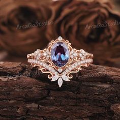 an engagement ring with a large blue stone surrounded by white diamonds on top of a piece of wood