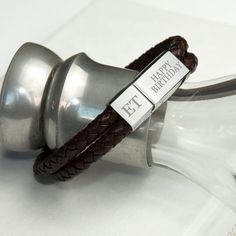 a brown leather bracelet with a metal hook on the end and a happy birthday tag attached to it