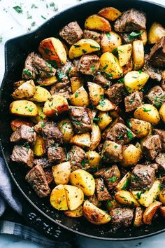 steak and potatoes in a skillet with parsley on the side, ready to be eaten