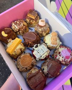 a pink box filled with lots of different types of donuts and waffles