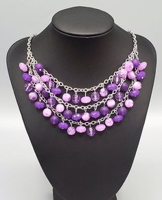 "Fairytale Timelessness": Varying in shape and opacity, a mismatched collection of light and dark purple crystal-like beads drip from the shimmery silver chains, creating an enchanted layered fringe below the collar. Features an adjustable clasp closure. Sold as one individual necklace. Includes one pair of matching earrings. Purple Beaded Chain Jewelry For Party, Adjustable Purple Beaded Necklace With Dangling Beads, Purple Faceted Beads Jewelry For Party, Purple Party Necklace With Chain Detail, Purple Jewelry With Faceted Beads For Party, Elegant Purple Beaded Necklace With Dangling Beads, Purple Chain Necklace For Party, Purple Dangling Beads Jewelry For Party, Adjustable Purple Beaded Dangle Necklaces