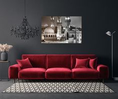 a living room with a red couch and chandelier hanging from the ceiling in front of a gray wall