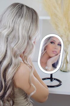 a woman looking at her reflection in the mirror with long blonde hair and blue eyes