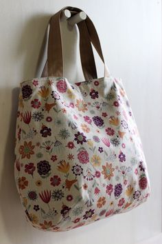 a bag hanging on the wall with flowers all over it and two handles in front