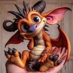 a small toy dragon sitting on top of someone's hand with it's eyes wide open