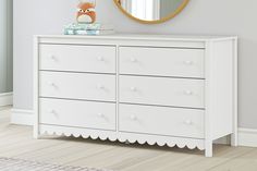 a white dresser with a mirror on top of it and a stuffed animal in the corner