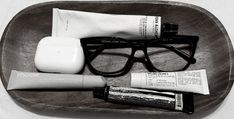 a pair of glasses, toothpaste and other personal care items sit on a tray