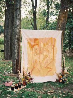 an orange and white painting is on display in front of some trees with lights strung from them