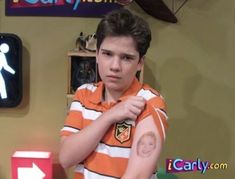 the young boy is wearing an orange and white striped shirt with patches on his arm