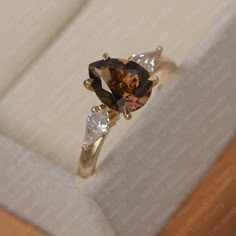 an engagement ring with two brown and white diamonds on it's side, sitting in a box