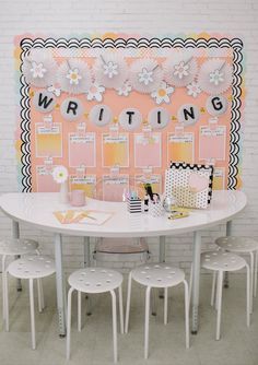 a white table with four chairs and a writing board on the wall behind it that says writing