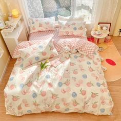 a bed with pink and blue flowers on it in front of a window next to a wooden floor