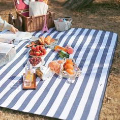 a picnic blanket on the ground with food and drinks