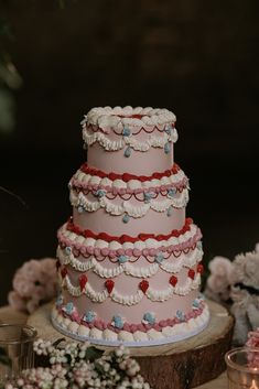 a three tiered wedding cake sitting on top of a wooden table next to flowers