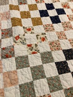 an old quilt is laying on top of a bed sheet that has flowers and leaves all over it