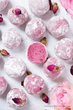 powdered sugar covered donuts and pink flowers on a white surface with text overlay