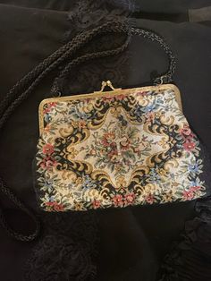 A vintage bag with an antique Victorian vibes look. This evening bag has a colorful needle point look (soft cloth fabric) in florals in front against a white background. It has a gold frame with a kiss clasp. Solid black in the back and it has a black cord like shoulder strap. *Rosary accent not included *Era: 1970's *Label: None *Fabric: Feels like cotton or a cotton blend *Condition: Gently used / No Flaws *Size: The bag measures 5 inches down and 8 inches across and it has a 19 inches strap Vintage Embroidered Evening Bags, Vintage Evening Bag In Tapestry Material, Vintage Tapestry Bag For Evening, Vintage Embroidered Clutch Evening Bag, Vintage Tapestry Bag For Formal Occasions, Vintage Tapestry Shoulder Bag For Evening, Embroidered Rectangular Bag For Vintage Events, Vintage Tapestry Pouch Bag, Vintage Formal Tapestry Bag