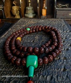 a green and red beaded necklace sitting on top of a table next to other items