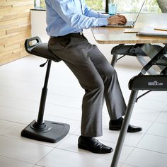 a man sitting at a desk with his laptop on the table and legs crossed out