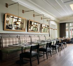 an empty restaurant with tables and chairs in front of large mirrors hanging on the wall