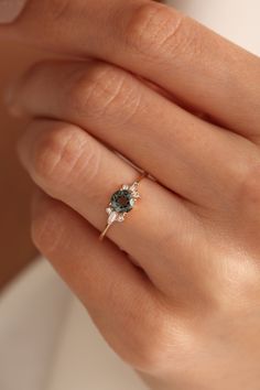 a woman's hand with a ring on it and an emerald stone in the middle