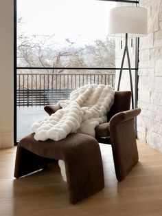 a chair with a blanket on it in front of a window