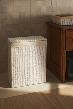 a white basket sitting next to a wooden cabinet