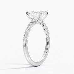 a white gold engagement ring with an oval cut diamond on the side, surrounded by round brilliant diamonds