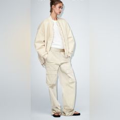 High-Waisted Pants With Side Pockets, False Back Flap Pockets, And Patch Pockets At Legs. Front Zip And Metal Hook Closure. Beige Utility Parachute Pants For Fall, Fall Utility Beige Parachute Pants, Beige Cargo Style Parachute Pants For Fall, Beige Cargo Bottoms For Fall, Beige Relaxed Fit Pants For Fall, Beige Cargo Style Bottoms, Neutral Relaxed Fit High-waisted Pants, Beige Relaxed Fit Cargo Pants For Fall, Khaki Cargo Pants For Workwear, Spring