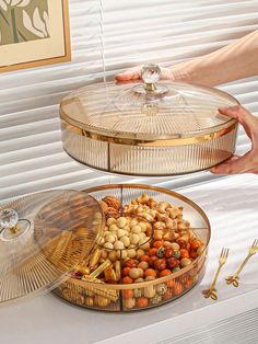 two serving trays with food on them sitting on a table next to a window