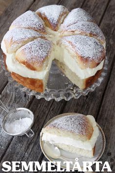 a cake sitting on top of a wooden table next to a glass bowl filled with powdered sugar