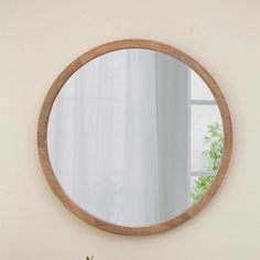 a round mirror hanging on the side of a wall next to a potted plant