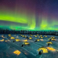 an igloose is lit up in the sky with aurora lights above it