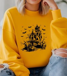 a woman wearing a yellow sweatshirt with a black and white image of a house on it