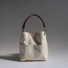 a white purse with brown handles on a gray background