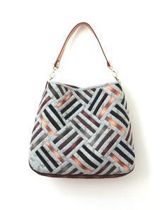 a handbag hanging on the wall in front of a white wall with an orange and black pattern