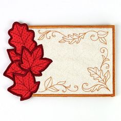 a card with a red leaf on it and a white paper backing in the shape of a rectangle