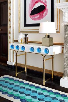 a white console table with blue and pink decorations on it in front of a painting