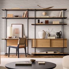 a living room filled with furniture next to a wall mounted book shelf and a coffee table