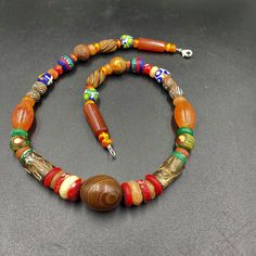 a beaded necklace with multicolored beads on a gray surface and a silver clasp