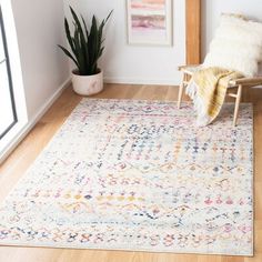 a living room with a rug, chair and potted plant on the floor in front of a window