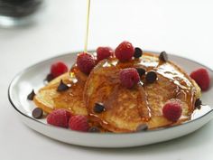 pancakes with syrup and raspberries on a plate