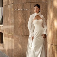 a woman in a white dress standing next to a wall