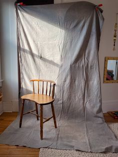 a chair sitting on top of a wooden floor in front of a gray tarp