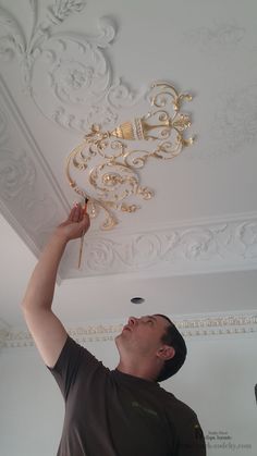 a man is working on the ceiling in his living room with gold decorations and lights