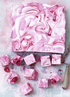 pink swirled cake next to a knife and some cubes of ice cream on a table