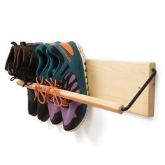 a wooden shoe rack with several pairs of shoes hanging from it's sides and one pair of sneakers on the other side